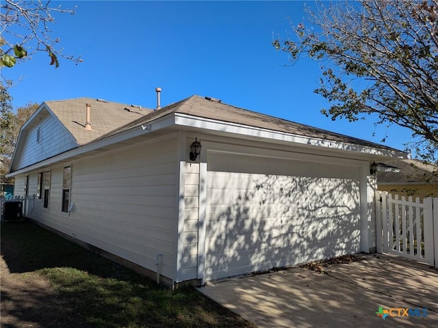 view of side of home featuring central AC and a garage