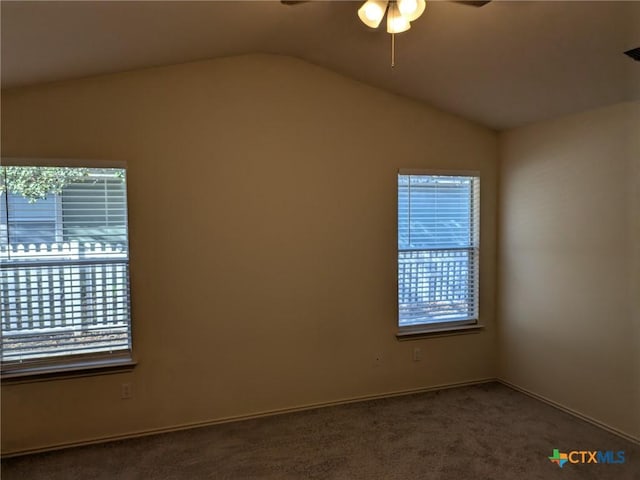 empty room featuring dark colored carpet, ceiling fan, a healthy amount of sunlight, and lofted ceiling