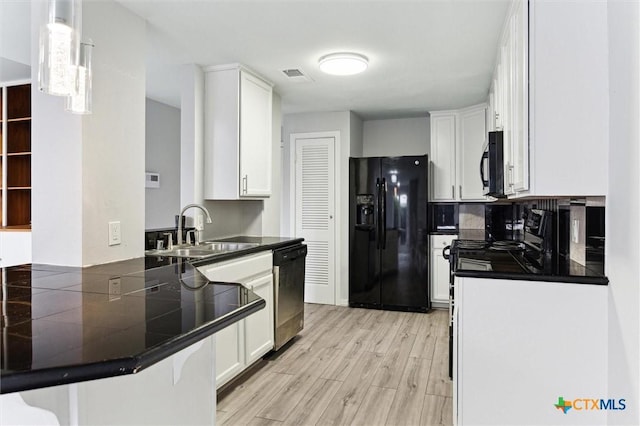 3300 Yorktown St Unit 13, Houston, TX 77056 - kitchen with black appliances, a peninsula, light wood-style flooring, and white cabinetry