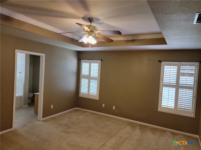 spare room with a textured ceiling, light carpet, ceiling fan, a raised ceiling, and crown molding