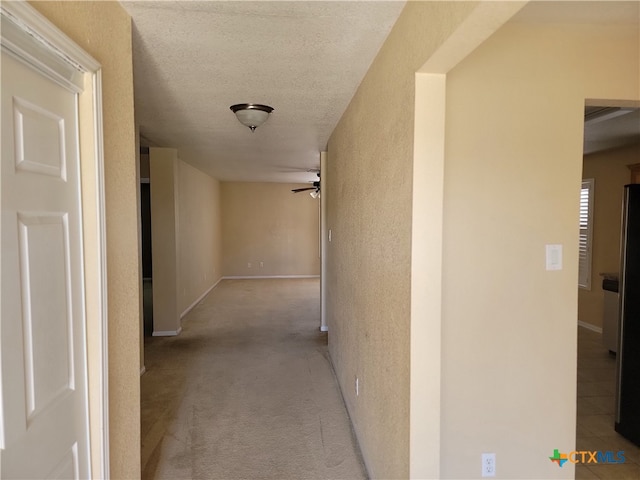 hallway featuring a textured ceiling and light carpet