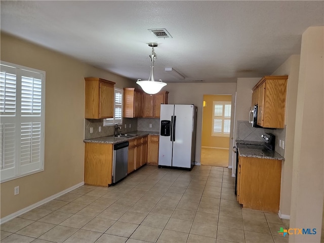 kitchen featuring stainless steel appliances, plenty of natural light, sink, and decorative light fixtures