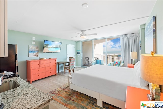 bedroom with access to outside, light wood-type flooring, stainless steel refrigerator, sink, and ceiling fan