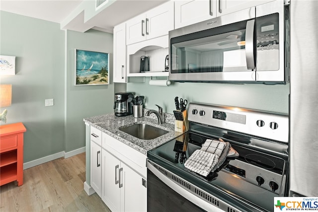 kitchen featuring stainless steel appliances, light hardwood / wood-style floors, light stone counters, sink, and white cabinetry