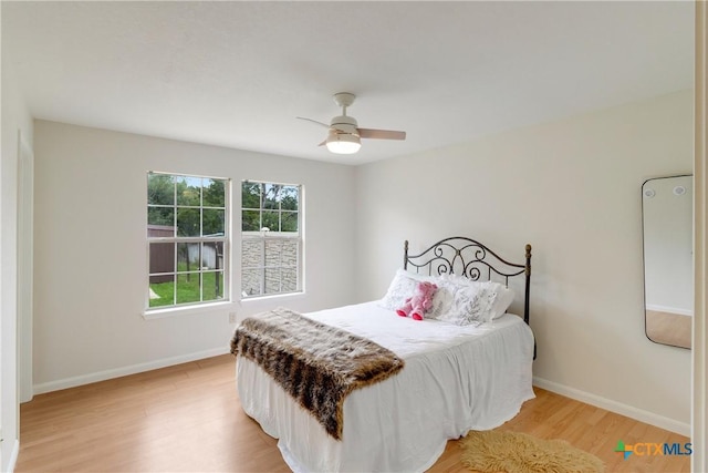 bedroom featuring a ceiling fan, light wood-style flooring, and baseboards