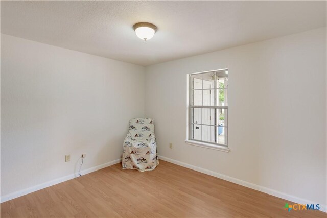 spare room featuring baseboards and light wood-type flooring