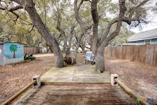 view of yard with a fenced backyard, a deck, a storage shed, and an outdoor structure