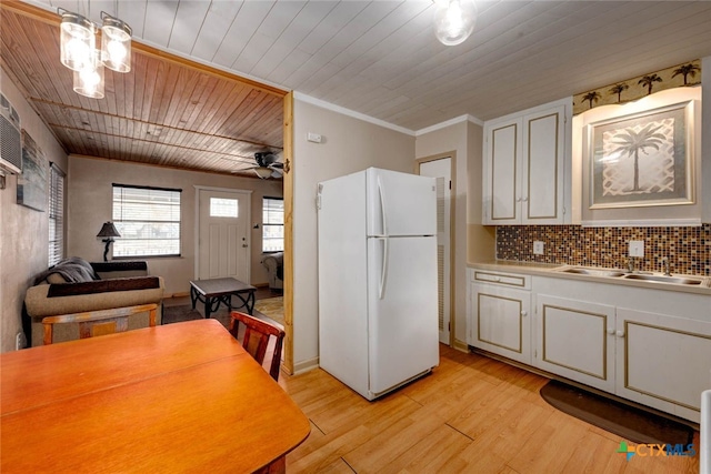 kitchen with backsplash, light wood-style flooring, wooden ceiling, freestanding refrigerator, and a sink