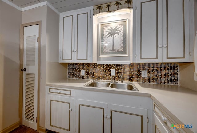 kitchen featuring decorative backsplash, light countertops, white cabinetry, and a sink