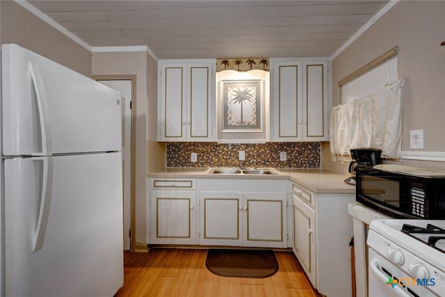 kitchen featuring crown molding, light countertops, light wood-style flooring, white appliances, and a sink