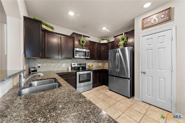 1401 Juneberry Park Dr, Temple, TX 76502 - kitchen featuring stainless steel appliances, a sink, light tile patterned flooring, dark brown cabinets, and dark stone counters