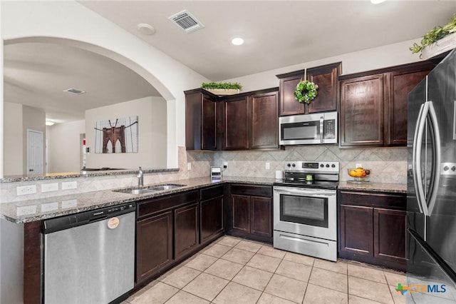 1401 Juneberry Park Dr, Temple, TX 76502 - kitchen featuring stainless steel appliances, a sink, light stone counters, light tile patterned floors, and dark brown cabinets