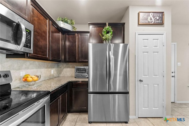 1401 Juneberry Park Dr, Temple, TX 76502 - kitchen featuring appliances with stainless steel finishes, light tile patterned flooring, dark brown cabinetry, light stone countertops, and tasteful backsplash