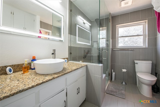 bathroom with tile patterned floors, a shower with door, vanity, and toilet