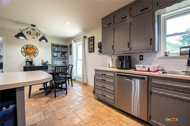 kitchen featuring backsplash, dishwasher, hanging light fixtures, and sink