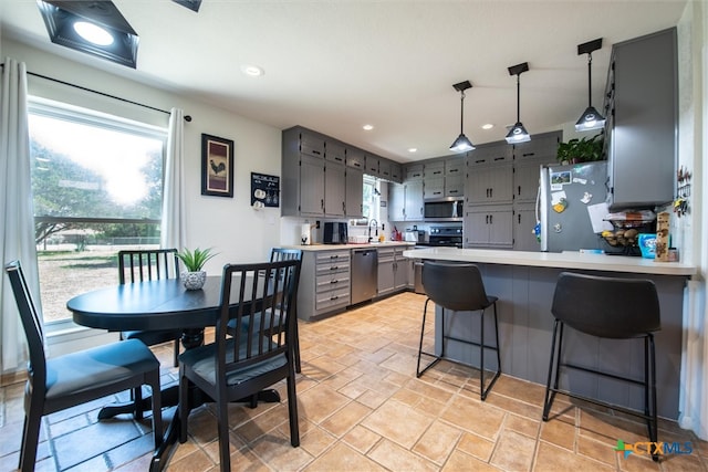 kitchen with gray cabinetry, a healthy amount of sunlight, kitchen peninsula, and stainless steel appliances