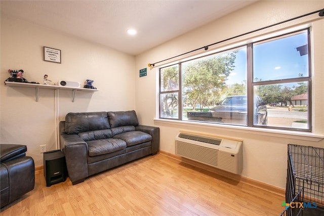 living room with light hardwood / wood-style flooring and a wall unit AC