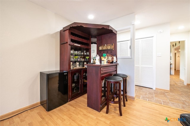 bar featuring black refrigerator and hardwood / wood-style flooring