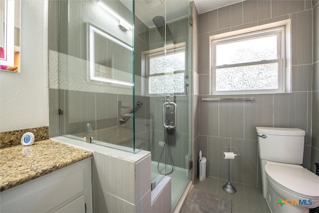 bathroom with tile patterned flooring, vanity, toilet, and walk in shower