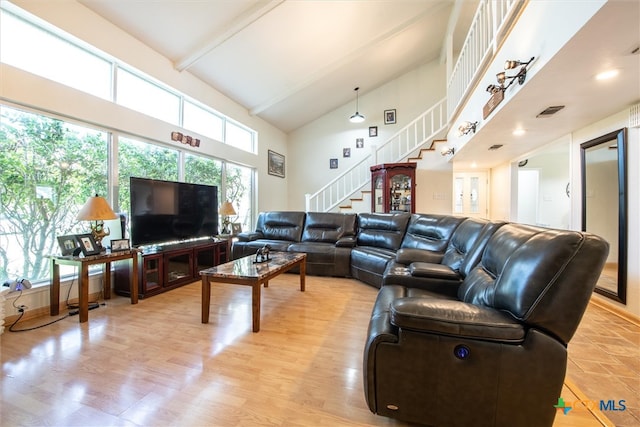 living room with beam ceiling, light wood-type flooring, and high vaulted ceiling