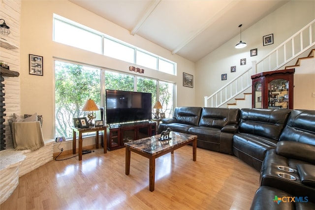 living room with beam ceiling, wood-type flooring, a fireplace, and high vaulted ceiling