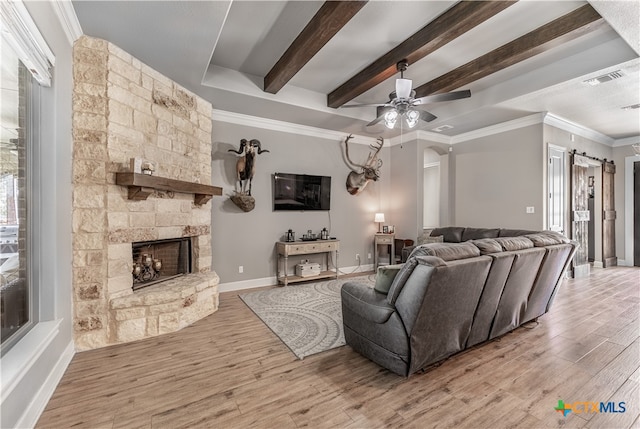 living room with a fireplace, beam ceiling, light wood-type flooring, and crown molding