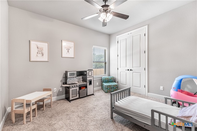 carpeted bedroom featuring ceiling fan and a closet