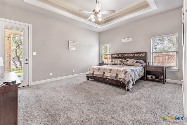 bedroom with ceiling fan, a raised ceiling, carpet floors, and access to outside