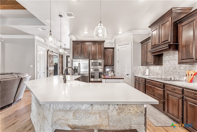 kitchen with appliances with stainless steel finishes, backsplash, a spacious island, light hardwood / wood-style flooring, and pendant lighting