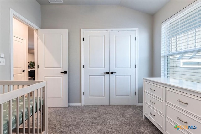 bedroom with a closet, visible vents, dark carpet, vaulted ceiling, and a crib