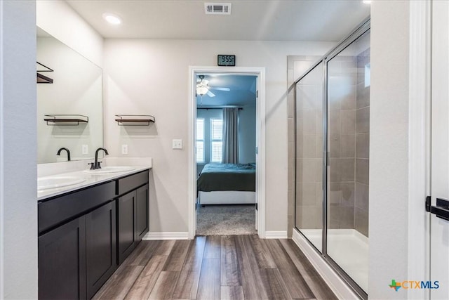 ensuite bathroom featuring visible vents, tiled shower, ensuite bath, wood finished floors, and a sink