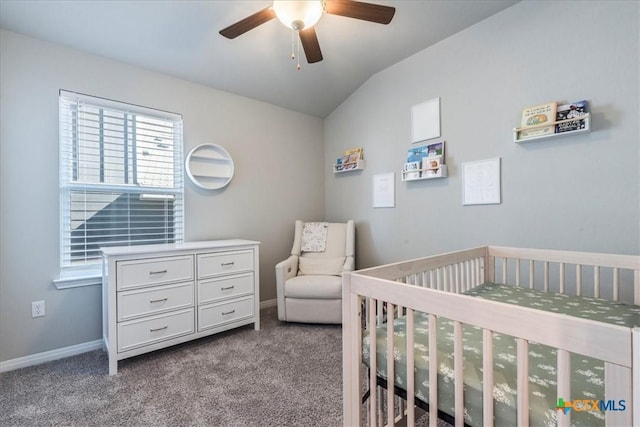 carpeted bedroom featuring lofted ceiling, ceiling fan, a crib, and baseboards