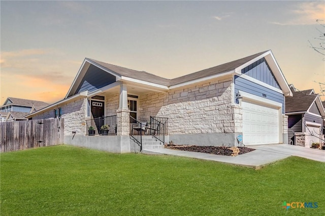 view of front of home with stone siding, board and batten siding, concrete driveway, and a yard