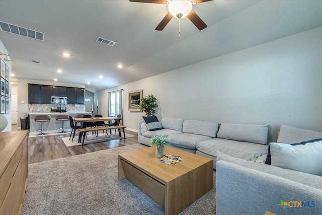 living room featuring recessed lighting, visible vents, lofted ceiling, and wood finished floors