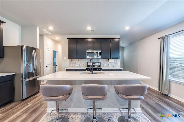 kitchen featuring a center island with sink, visible vents, appliances with stainless steel finishes, light countertops, and a sink