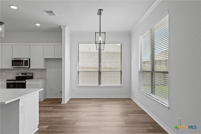 7915 Autumnwood Ln, Temple, TX 76502 - kitchen featuring stainless steel appliances, light countertops, ornamental molding, white cabinetry, and hanging light fixtures