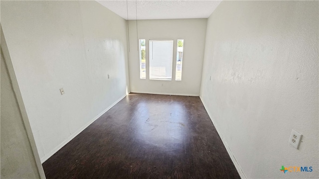 spare room with a textured ceiling and dark hardwood / wood-style floors