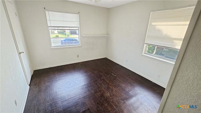 spare room featuring a wealth of natural light and dark hardwood / wood-style floors