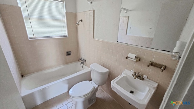 bathroom featuring tile patterned flooring, toilet, tile walls, and tiled shower / bath combo