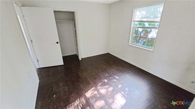 unfurnished bedroom with dark wood-type flooring and a closet