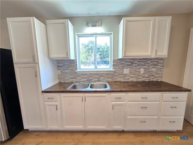 kitchen with refrigerator, sink, white cabinetry, and backsplash