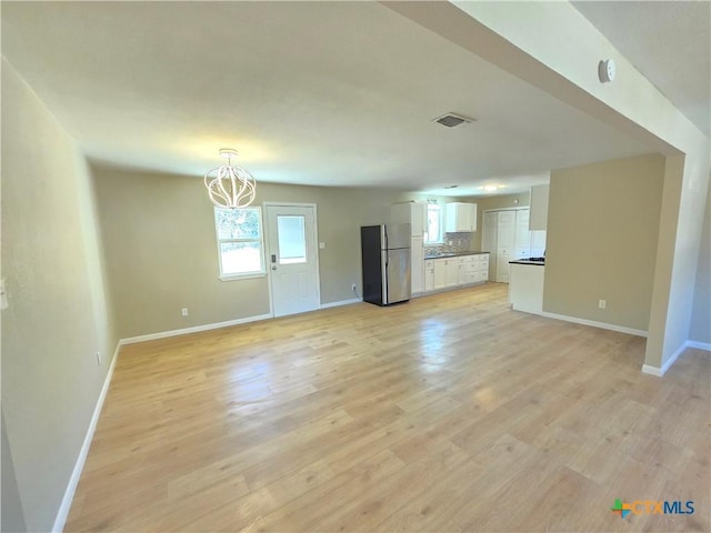 unfurnished living room featuring light hardwood / wood-style floors and a notable chandelier