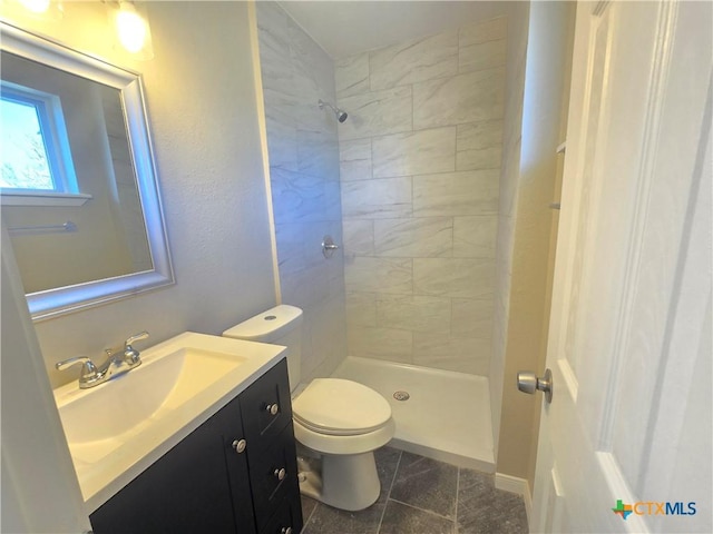 bathroom featuring a tile shower, tile patterned flooring, vanity, and toilet