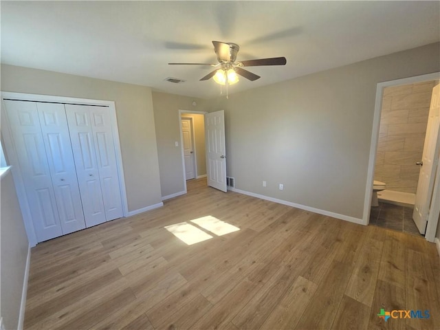 unfurnished bedroom featuring a closet, light hardwood / wood-style flooring, ensuite bath, and ceiling fan