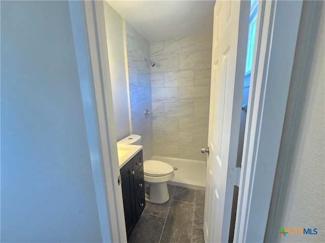 bathroom featuring vanity, toilet, and a tile shower