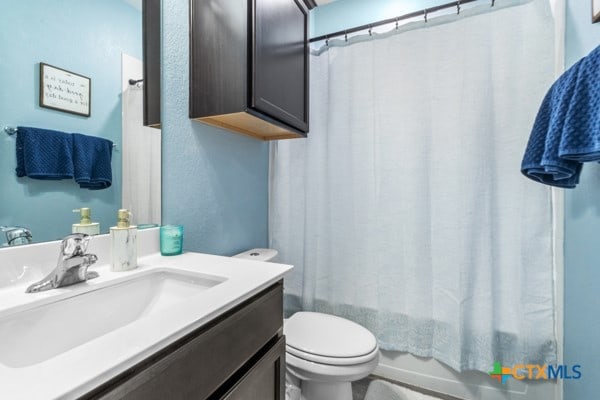 full bathroom with toilet, vanity, and shower / bathtub combination with curtain