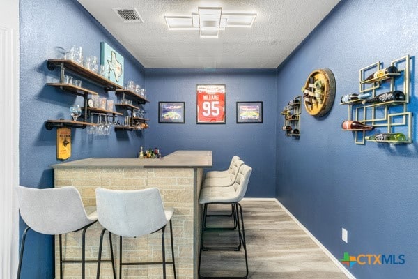 bar with a textured ceiling and wood-type flooring