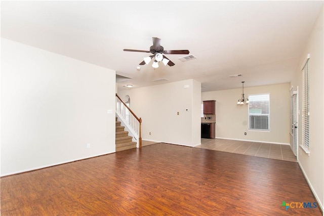 10113 Orion Dr, Temple, TX 76502 - unfurnished living room with stairs, light wood-style floors, visible vents, and ceiling fan with notable chandelier