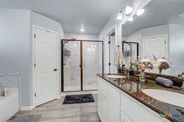 bathroom featuring a bath, double vanity, a sink, and a shower stall
