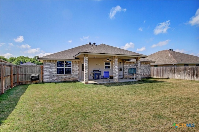back of property with a shingled roof, a patio area, a fenced backyard, a lawn, and a ceiling fan